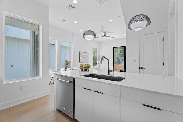 52 Robert T Martinez Jr St, Austin, TX 78702 - kitchen with a sink, stainless steel dishwasher, recessed lighting, hanging light fixtures, and white cabinetry