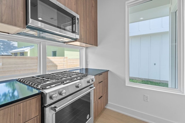 52 Robert T Martinez Jr St, Austin, TX 78702 - kitchen with appliances with stainless steel finishes, modern cabinets, baseboards, and dark countertops
