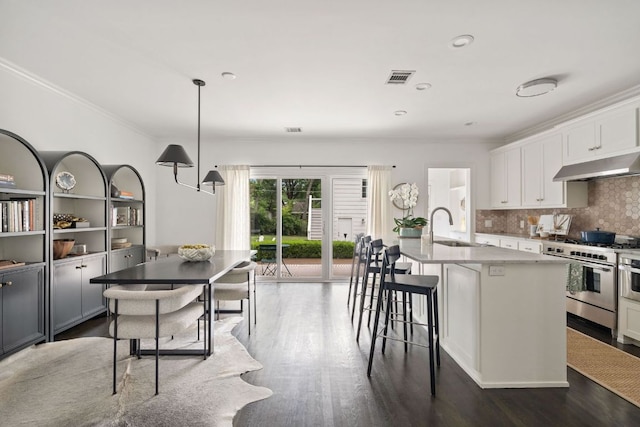1711 Mohle Dr, Austin, TX 78703 - kitchen with stainless steel range with gas stovetop, under cabinet range hood, a sink, crown molding, and dark wood-style floors