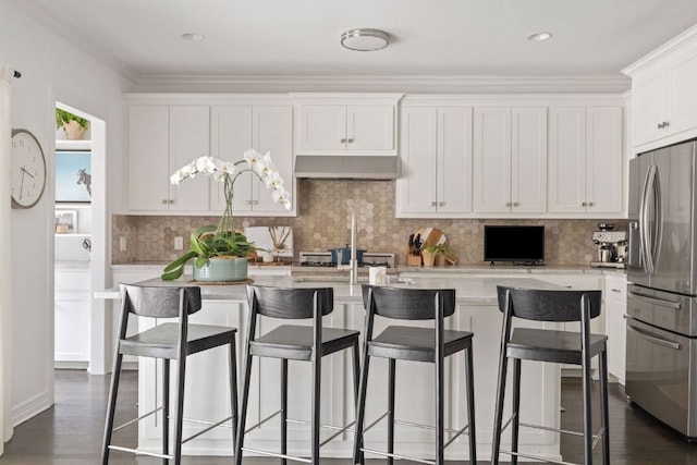 1711 Mohle Dr, Austin, TX 78703 - kitchen with stainless steel fridge with ice dispenser, white cabinets, under cabinet range hood, a center island with sink, and dark wood finished floors