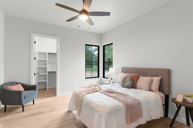 8341 Brewer Ln, Salado, TX 76571 - bedroom featuring wood finished floors, baseboards, a walk in closet, and a ceiling fan