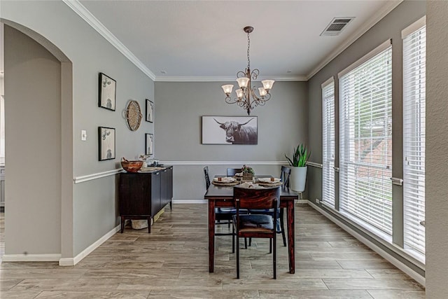 8002 Magic Mountain Cv, Round Rock, TX 78681 - dining room with arched walkways, crown molding, light wood-type flooring, a chandelier, and baseboards
