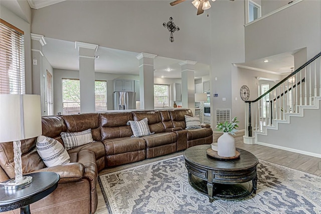 8002 Magic Mountain Cv, Round Rock, TX 78681 - living room with ornate columns, light wood finished floors, ceiling fan, a high ceiling, and stairs