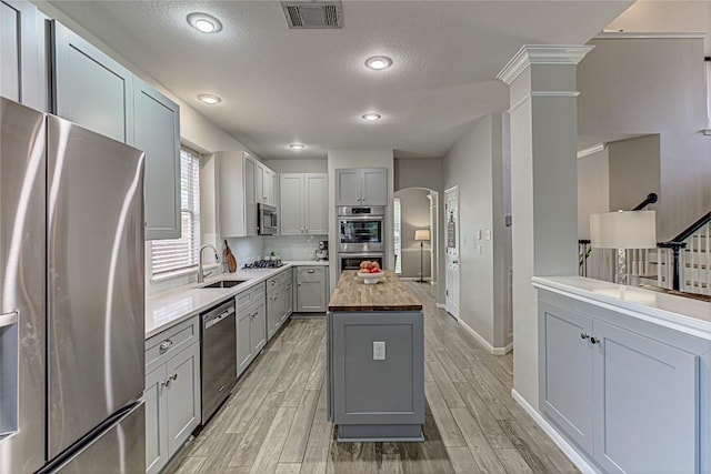 8002 Magic Mountain Cv, Round Rock, TX 78681 - kitchen featuring appliances with stainless steel finishes, gray cabinets, arched walkways, butcher block countertops, and a kitchen island