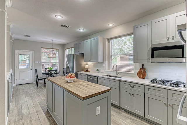 8002 Magic Mountain Cv, Round Rock, TX 78681 - kitchen with butcher block countertops, stainless steel appliances, gray cabinetry, backsplash, and recessed lighting