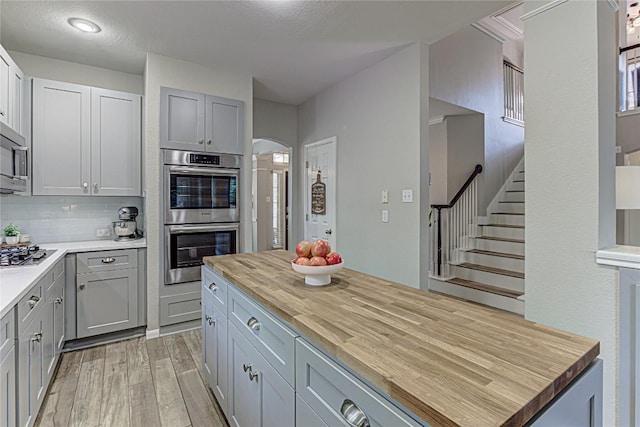 8002 Magic Mountain Cv, Round Rock, TX 78681 - kitchen with wood counters, appliances with stainless steel finishes, light wood finished floors, gray cabinetry, and arched walkways