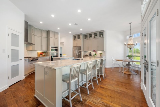 1701 Mira Vis, Leander, TX 78641 - kitchen featuring wall chimney exhaust hood, gray cabinetry, a spacious island, stainless steel appliances, and a chandelier