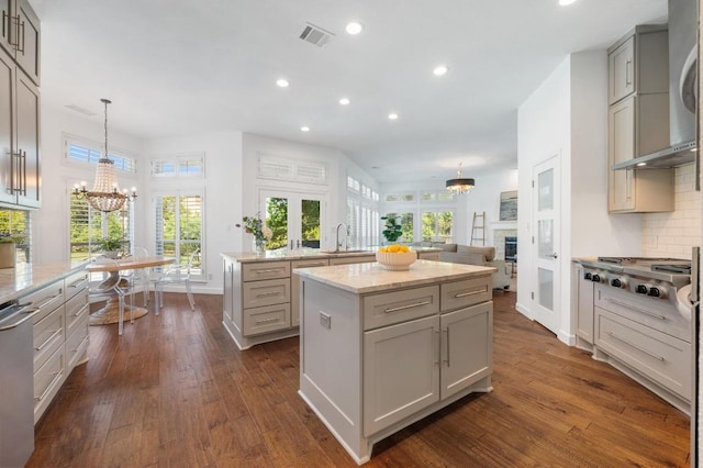 1701 Mira Vis, Leander, TX 78641 - kitchen featuring a center island, a chandelier, stainless steel appliances, a sink, and wall chimney range hood