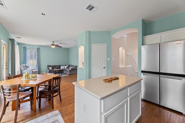 2100 Campfield Pkwy, Austin, TX 78745 - kitchen with freestanding refrigerator, ceiling fan, arched walkways, white cabinetry, and dark wood-style flooring