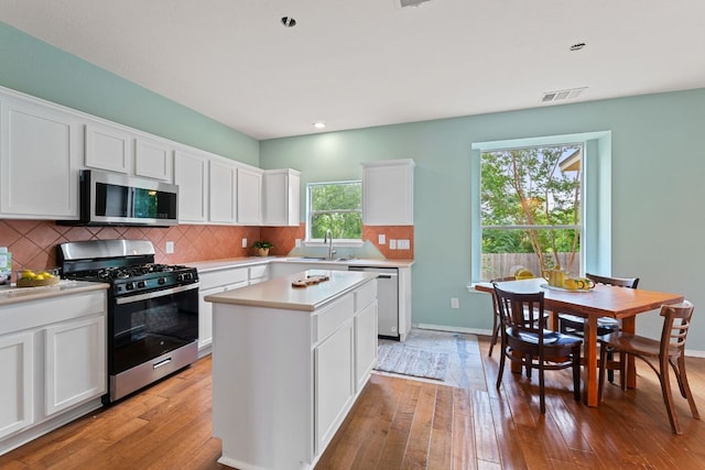 2100 Campfield Pkwy, Austin, TX 78745 - kitchen featuring stainless steel appliances, light countertops, a center island, light wood-style flooring, and backsplash