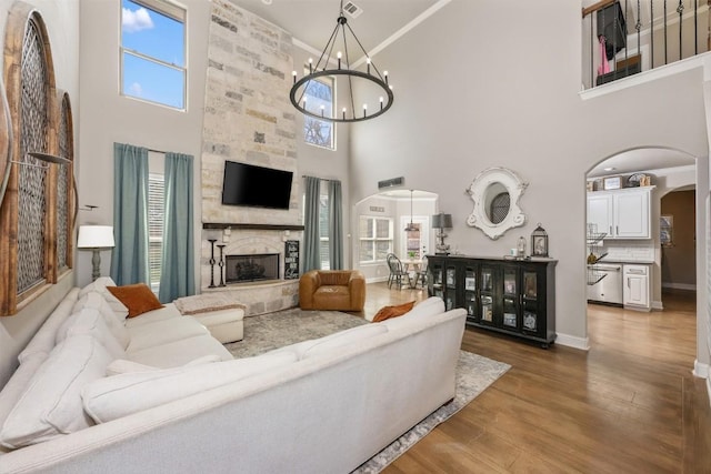2015 Th Jones Mill Way, Salado, TX 76571 - living area with arched walkways, a towering ceiling, a chandelier, a stone fireplace, and wood finished floors