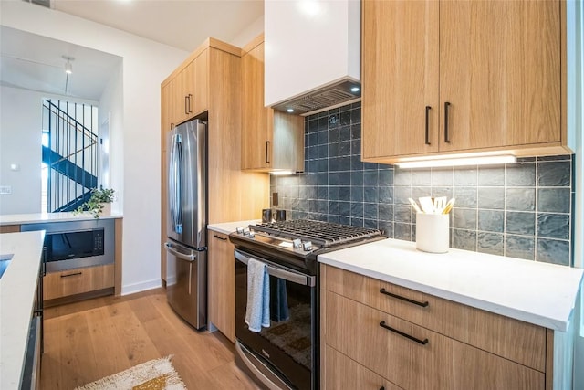 700 Denson Dr Unit 1104, Austin, TX 78752 - kitchen with appliances with stainless steel finishes, premium range hood, light wood finished floors, light countertops, and decorative backsplash