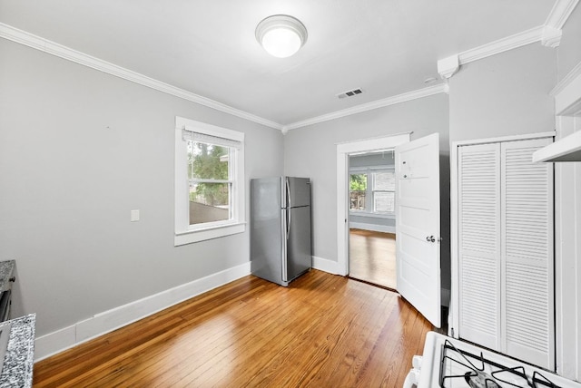 2032 E Cesar Chavez St, Austin, TX 78702 - unfurnished bedroom with freestanding refrigerator, ornamental molding, light wood-style floors, baseboards, and a closet