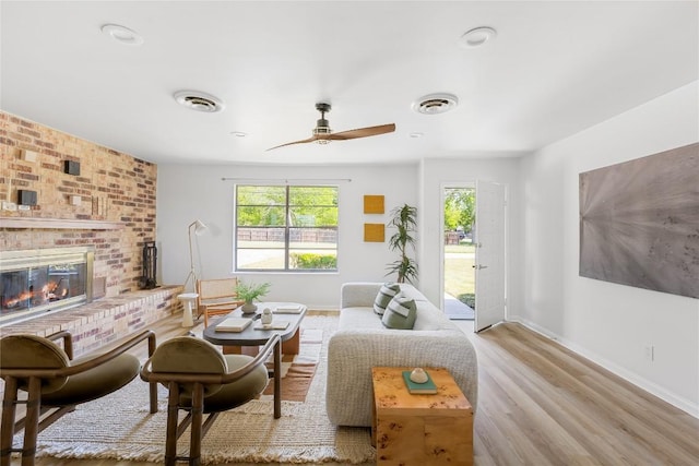 304 W Bee St, Lockhart, TX 78644 - living area featuring a ceiling fan, baseboards, a brick fireplace, and wood finished floors