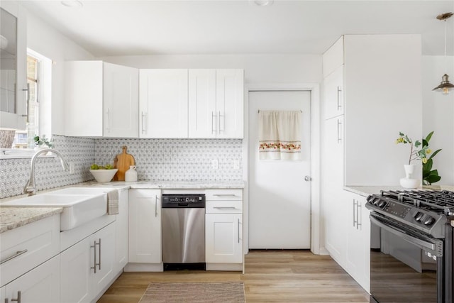 304 W Bee St, Lockhart, TX 78644 - kitchen with a sink, black gas range, stainless steel dishwasher, decorative backsplash, and white cabinetry