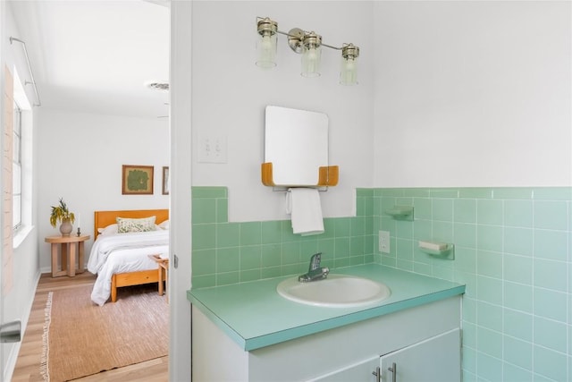 304 W Bee St, Lockhart, TX 78644 - bathroom featuring tile walls, vanity, wood finished floors, ensuite bathroom, and wainscoting
