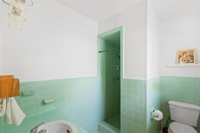 304 W Bee St, Lockhart, TX 78644 - bathroom featuring tile walls, tiled shower, toilet, and wainscoting