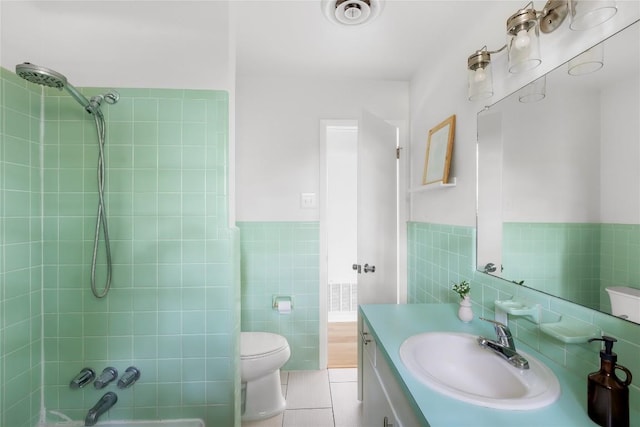 304 W Bee St, Lockhart, TX 78644 - full bathroom with tile walls, vanity, toilet, washtub / shower combination, and a wainscoted wall
