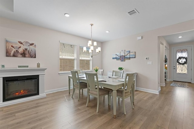 3227 Drago Dr, Round Rock, TX 78665 - dining room featuring a chandelier, light wood finished floors, baseboards, recessed lighting, and a glass covered fireplace