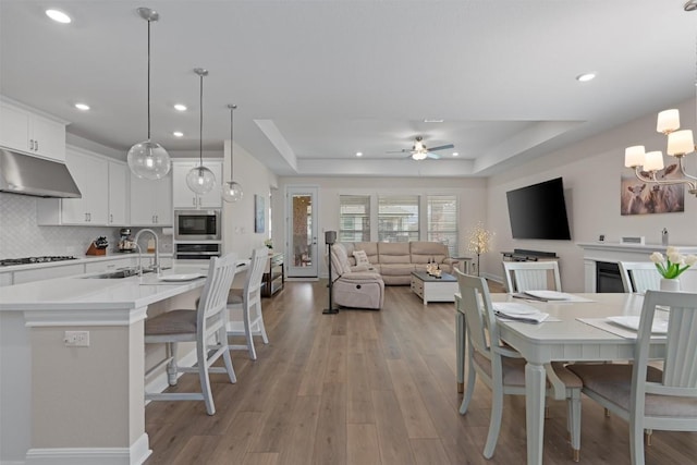 3227 Drago Dr, Round Rock, TX 78665 - dining area featuring a tray ceiling, recessed lighting, light wood-style floors, a ceiling fan, and a chandelier