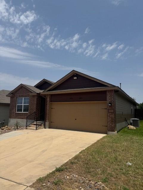 5511 Toledo Farm, San Antonio, TX 78222 - ranch-style home featuring an attached garage, central air condition unit, brick siding, concrete driveway, and a front yard
