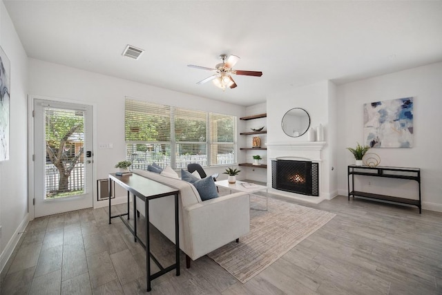 206 Skinner, Kyle, TX 78640 - living room with a lit fireplace, a ceiling fan, wood finished floors, and baseboards