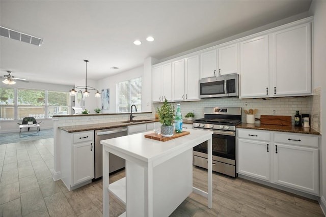 206 Skinner, Kyle, TX 78640 - kitchen featuring appliances with stainless steel finishes, a peninsula, decorative backsplash, white cabinetry, and a sink