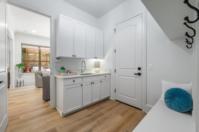 7 Sunview Rd, The Hills, TX 78738 - kitchen with a sink, light countertops, light wood-style flooring, white cabinets, and baseboards