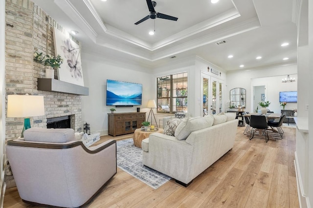 7 Sunview Rd, The Hills, TX 78738 - living area featuring a fireplace, ceiling fan, a tray ceiling, ornamental molding, and light wood-style flooring