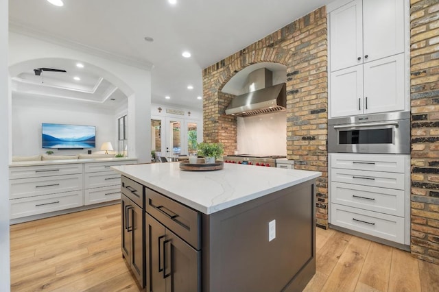 7 Sunview Rd, The Hills, TX 78738 - kitchen with oven, french doors, a center island, light wood-style flooring, and light stone countertops