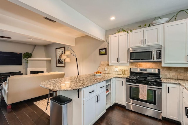 606 W Lynn St Unit 16, Austin, TX 78703 - kitchen featuring appliances with stainless steel finishes, a peninsula, tasteful backsplash, white cabinets, and recessed lighting