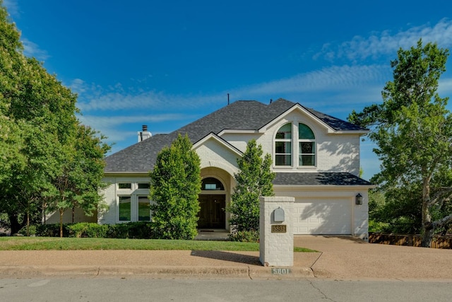 5801 Fox Chapel Dr, Austin, TX 78746 - traditional-style house featuring driveway, an attached garage, a shingled roof, brick siding, and a chimney