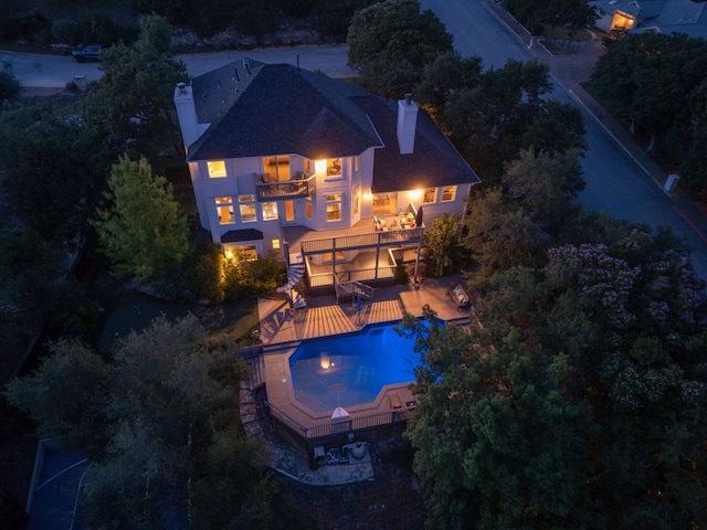 5801 Fox Chapel Dr, Austin, TX 78746 - back of house at night featuring a balcony, a chimney, and an outdoor pool