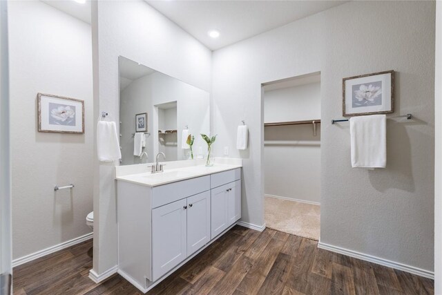6100 Shanjia Dr, Austin, TX 78724 - bathroom with double vanity, wood finished floors, toilet, a walk in closet, and baseboards