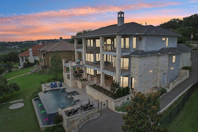 1353 Osprey Ridge Loop, Lago Vista, TX 78645 - back of property featuring a balcony, a patio, stucco siding, a yard, and stone siding