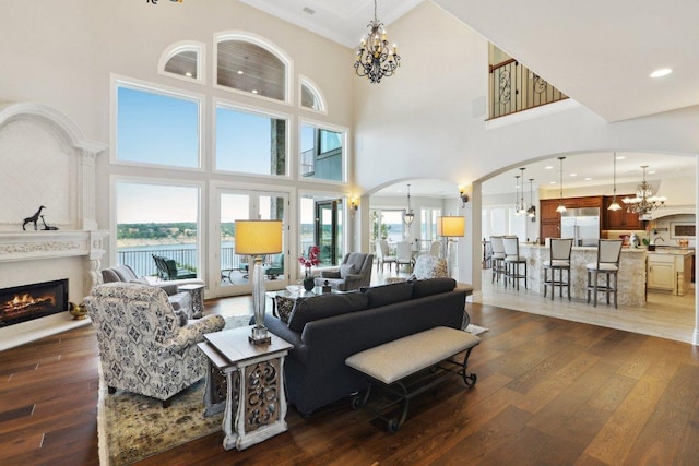 1353 Osprey Ridge Loop, Lago Vista, TX 78645 - living area featuring a chandelier, arched walkways, dark wood-style floors, and a high ceiling
