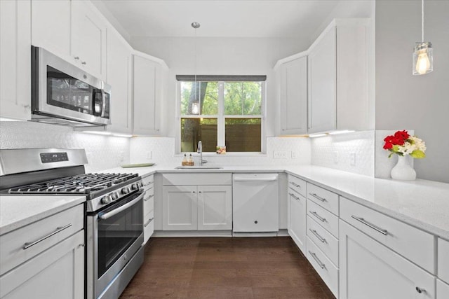 1500 Justin Ln Unit 2, Austin, TX 78757 - kitchen with appliances with stainless steel finishes, a sink, tasteful backsplash, white cabinetry, and dark wood-type flooring