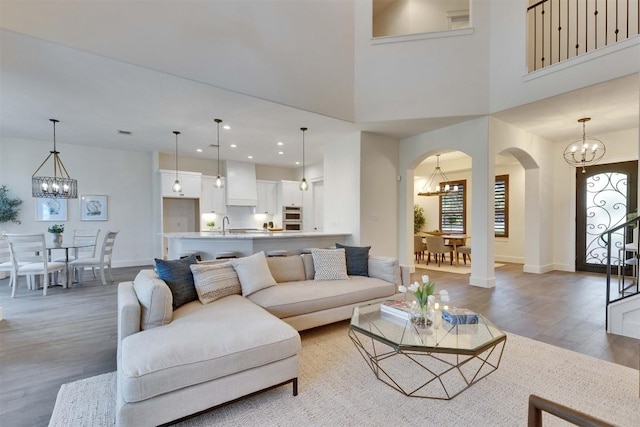 13601 Montview Dr, Austin, TX 78732 - living room featuring a chandelier, arched walkways, light wood finished floors, and recessed lighting