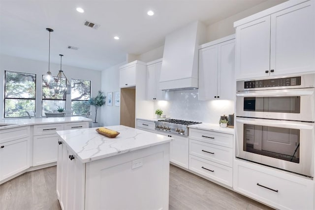 13601 Montview Dr, Austin, TX 78732 - kitchen with stainless steel appliances, premium range hood, a center island, light wood-style floors, and white cabinets