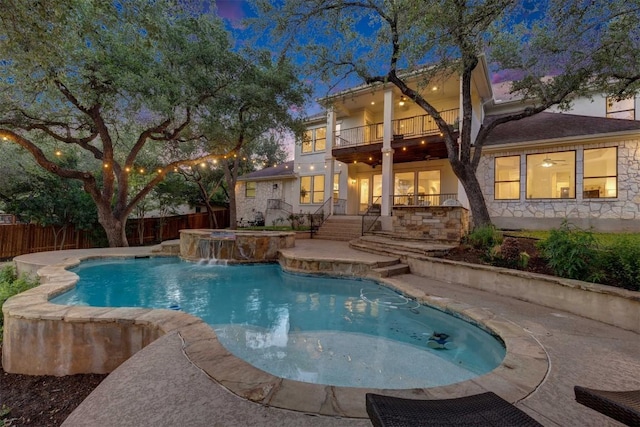 13601 Montview Dr, Austin, TX 78732 - back of property featuring a balcony, a fenced backyard, a patio, stone siding, and a pool with connected hot tub