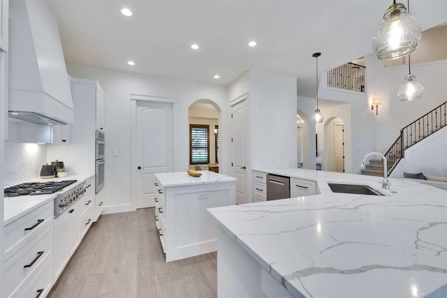 13601 Montview Dr, Austin, TX 78732 - kitchen featuring arched walkways, premium range hood, a kitchen island, stainless steel appliances, and light wood-style floors