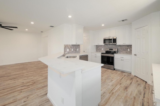 131 Roundup Dr, Liberty Hill, TX 78642 - kitchen featuring stainless steel appliances, a sink, a peninsula, white cabinets, and recessed lighting