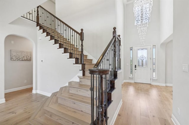 7840 Aria Loop, Austin, TX 78736 - entrance foyer featuring arched walkways, a towering ceiling, stairway, hardwood / wood-style floors, and baseboards