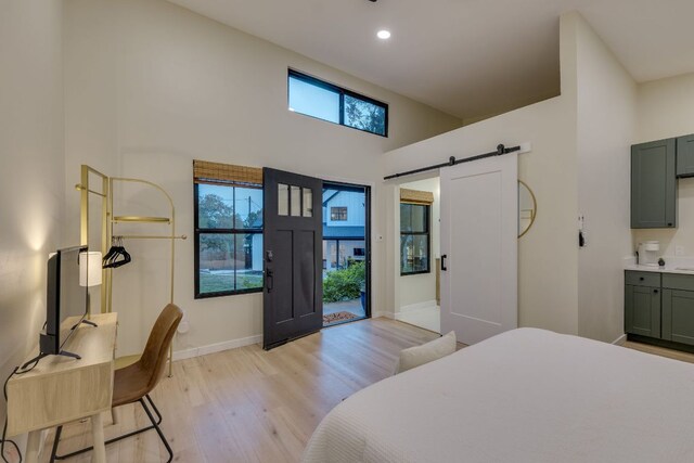 5904 Hudson Bend Rd, Austin, TX 78734 - bedroom with a barn door, light wood finished floors, multiple windows, recessed lighting, and a towering ceiling