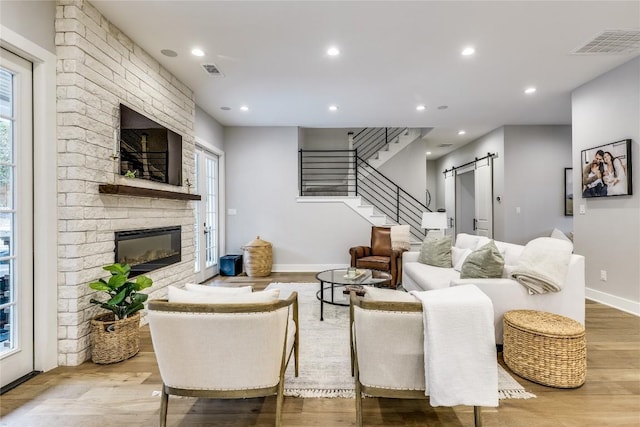 5904 Hudson Bend Rd, Austin, TX 78734 - living area with a barn door, a fireplace, wood finished floors, stairway, and recessed lighting