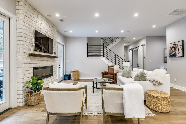 5904 Hudson Bend Rd, Austin, TX 78734 - living area featuring a barn door, a large fireplace, wood finished floors, stairway, and recessed lighting