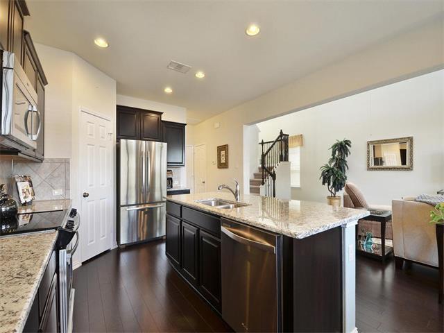 9944 Wading Pool Path, Austin, TX 78748 - kitchen featuring appliances with stainless steel finishes, dark wood-style flooring, a sink, light stone countertops, and decorative backsplash