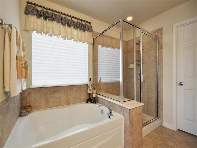 9944 Wading Pool Path, Austin, TX 78748 - bathroom with healthy amount of natural light, a garden tub, a shower stall, and tile patterned flooring