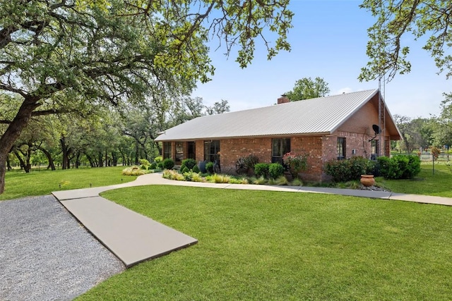 423 County Road 1010, Lampasas, TX 76550 - ranch-style home with a front lawn, a chimney, brick siding, and metal roof