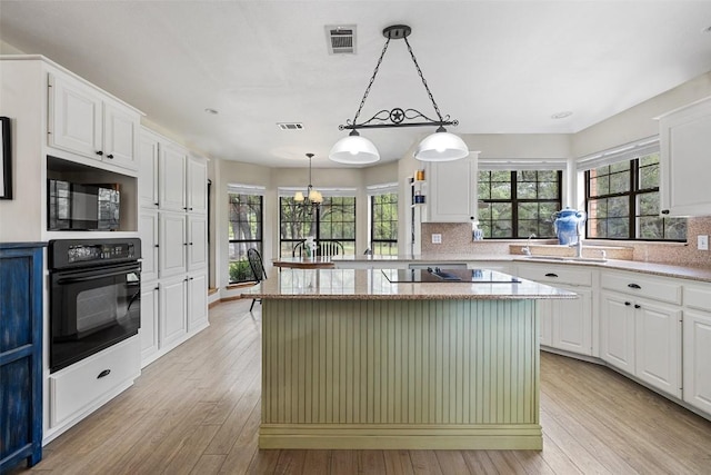 423 County Road 1010, Lampasas, TX 76550 - kitchen with black appliances, light wood-style floors, decorative backsplash, and white cabinets